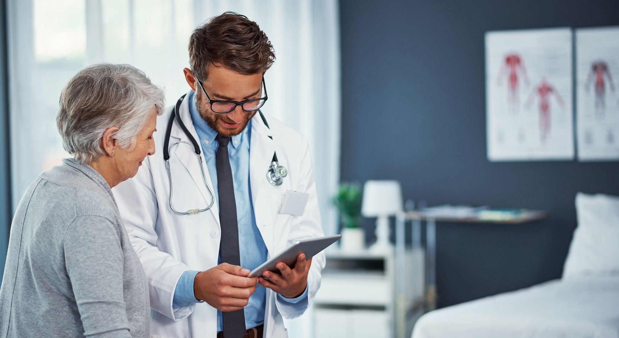 A doctor reviews information on a tablet with his patient.