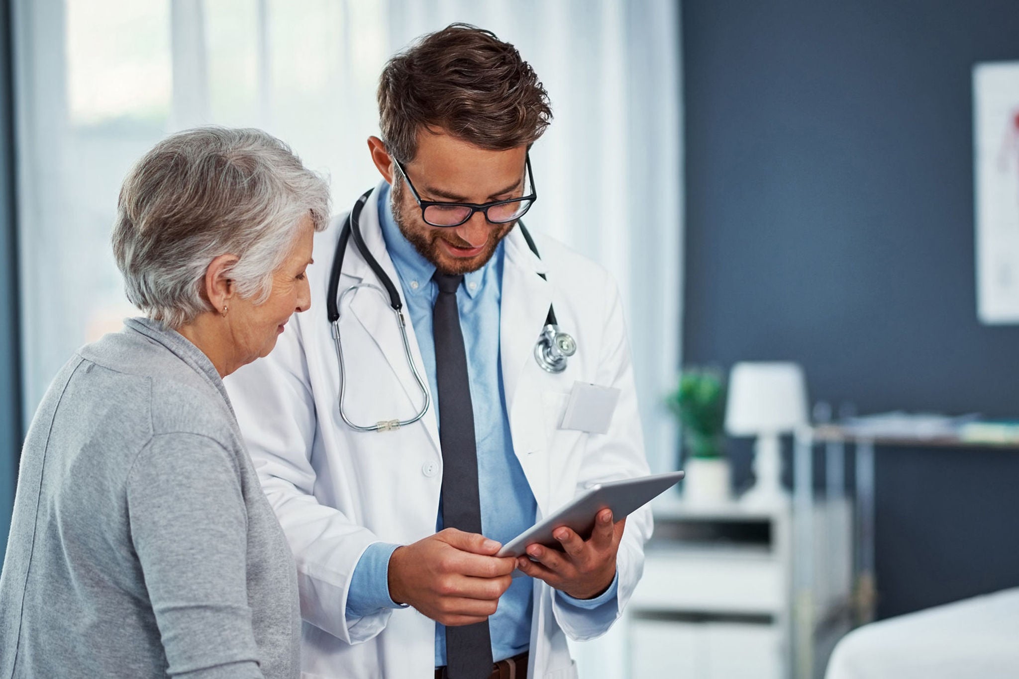 A doctor reviews information on a tablet with his patient.